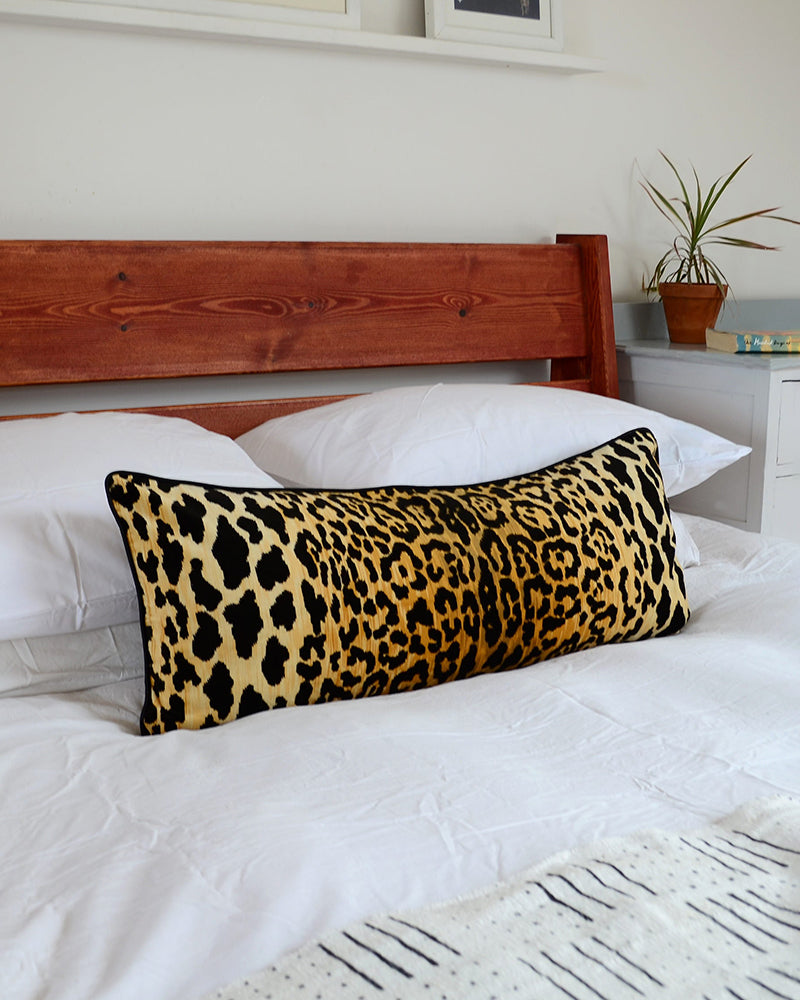Velvet leopard print lumbar pillow on a bed